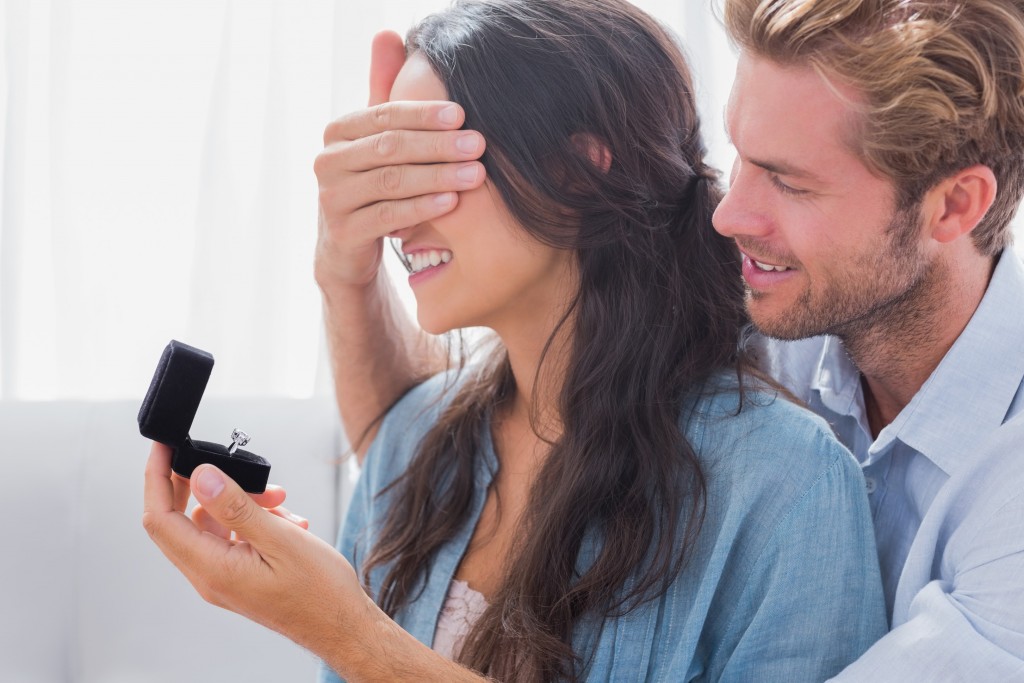 Man hiding his wifes eyes to offer her an engagement ring for a marriage proposal